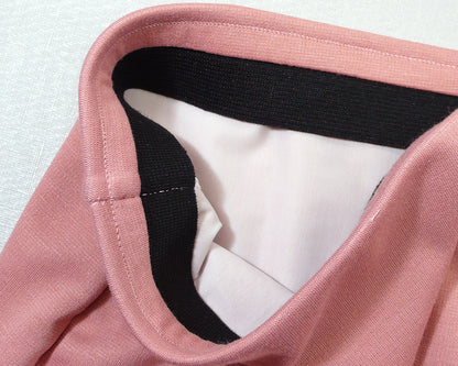 A photograph of the interior construction of the lined skirt, specifically the waistband section. White lining, black elastic band, and pink exterior fabric.