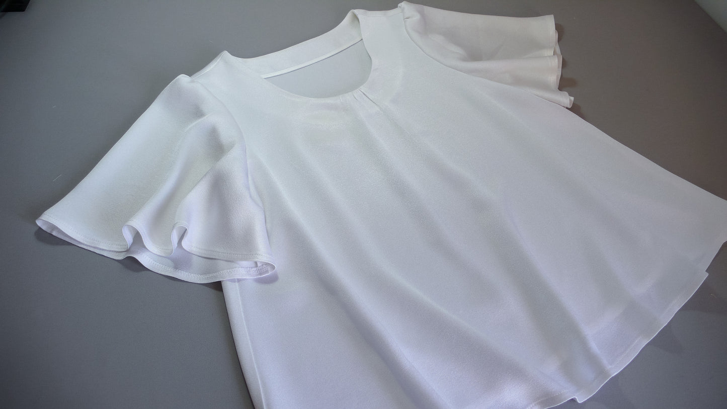 A white blouse laid out on a gray table. 